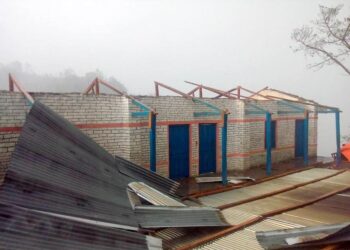 विद्यालयको छानो हावाहुरीले उडाएपछि विद्यार्थी खेलमैदानमा पढ्दै